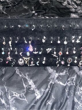Belly button and eyebrow ring collection on black velvet display stand